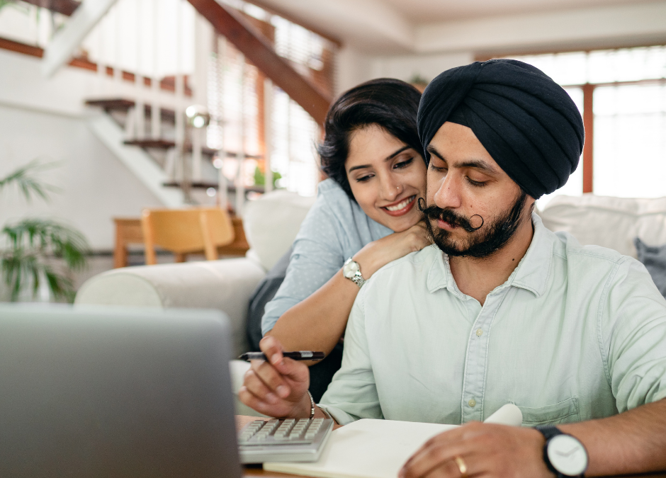 FREE Serious young Sikh man with hugging wife counting on calculator at home